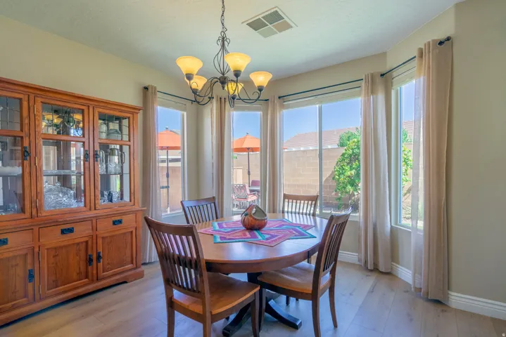 Bay window with multiple large glass panels, wood-finish flooring, recessed ceiling, and a five-light chandelier