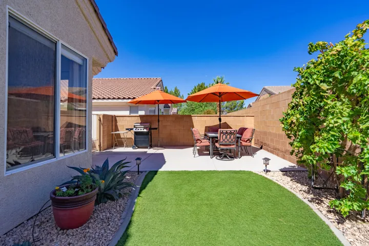 Paved patio area, artificial turf lawn, privacy wall, mature landscaping, exterior wall with window