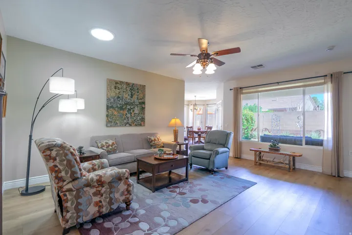 Living area with Cor-tec luxury vinyl wood-finish flooring, a ceiling fan, and a large window