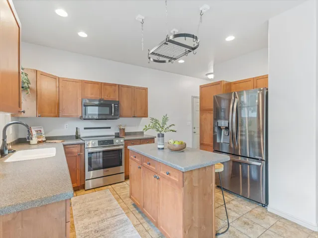 Kitchen featuring wood cabinetry, stainless steel appliances, a center island with countertop, recessed lighting, and tile flooring