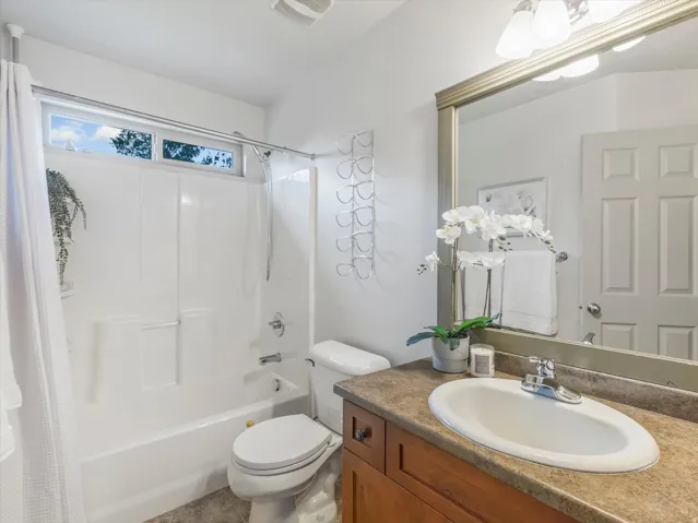 Single vanity with wood-finish cabinetry, a large framed mirror, and an integrated sink