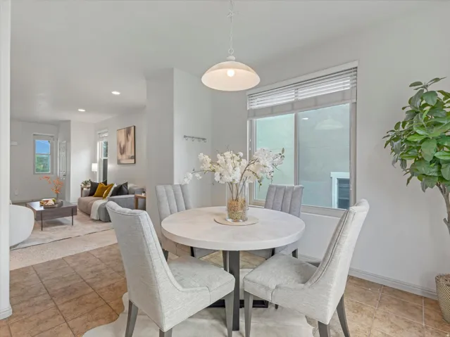 Modern dining area anchored by a round white table with a pedestal base, paired with upholstered dining chairs