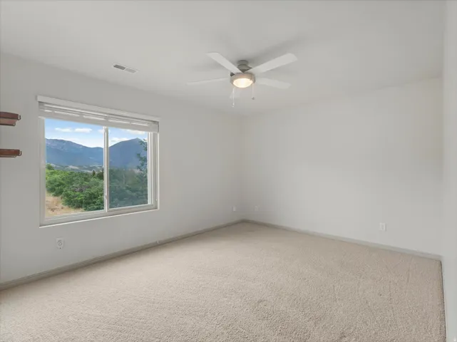 Recessed window with mountain scenery, wall-to-wall carpeting, and a ceiling fan with integrated lighting