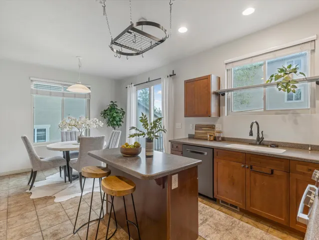 Kitchen featuring a central island, recessed lighting, wood-finish cabinetry, stainless steel dishwasher, and a pot rack