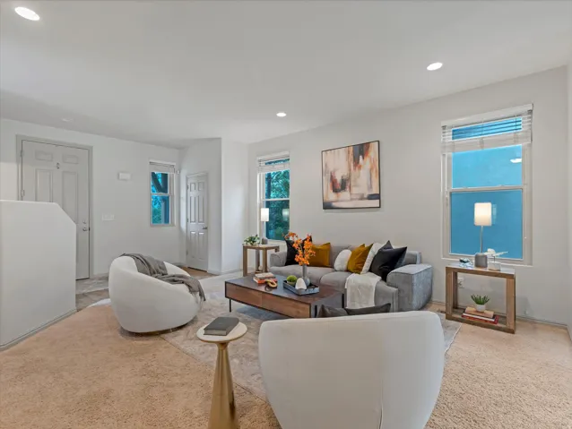 Recessed lighting, light-colored walls, and carpeting throughout the living area