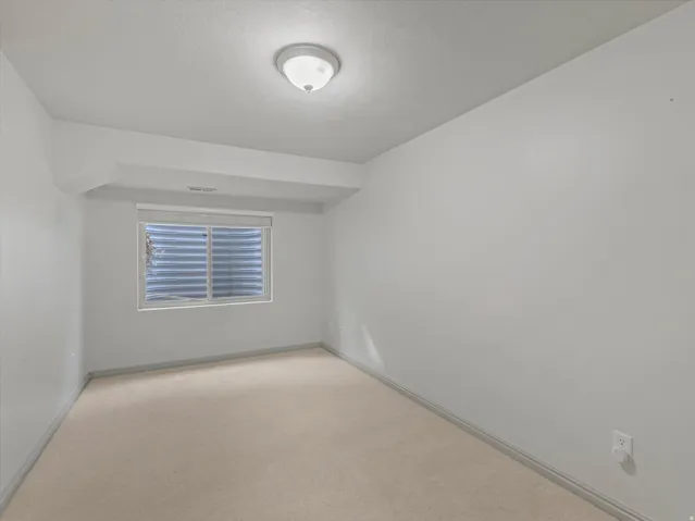 Neutral-toned wall paint, light-colored carpeting, and a window with blinds