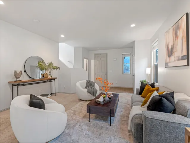 Open-concept living space featuring recessed lighting, a neutral color palette, and wood-finish flooring at the entry