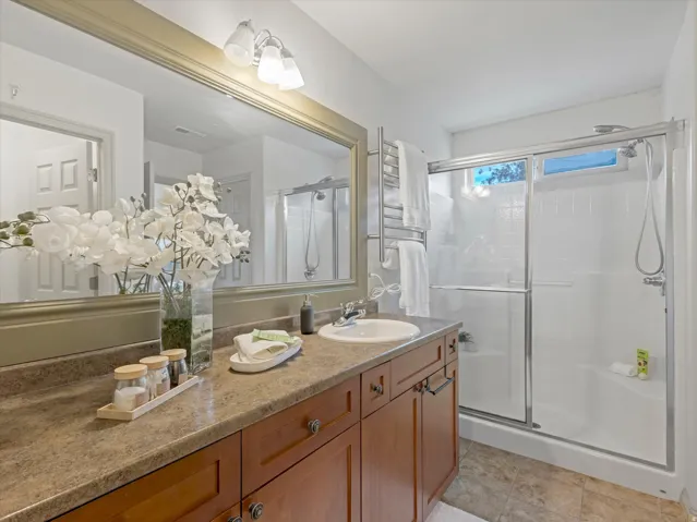 Vanity with integrated sink, wood-finish cabinetry, and a large framed mirror