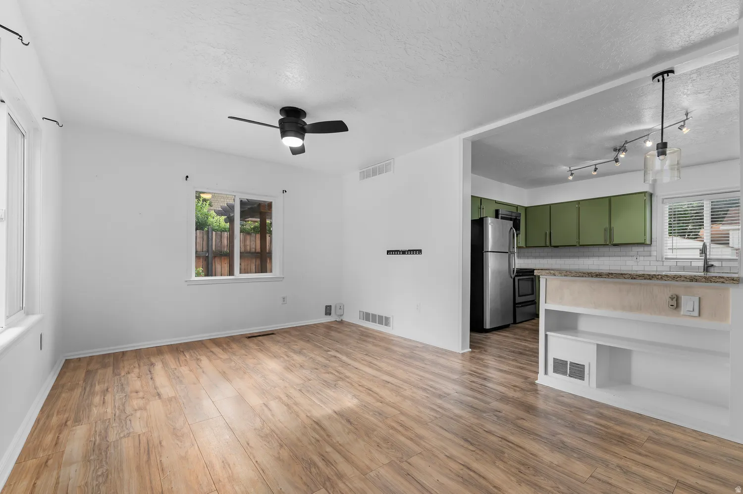 Wood-finish flooring, white walls, and a ceiling fan with integrated lighting