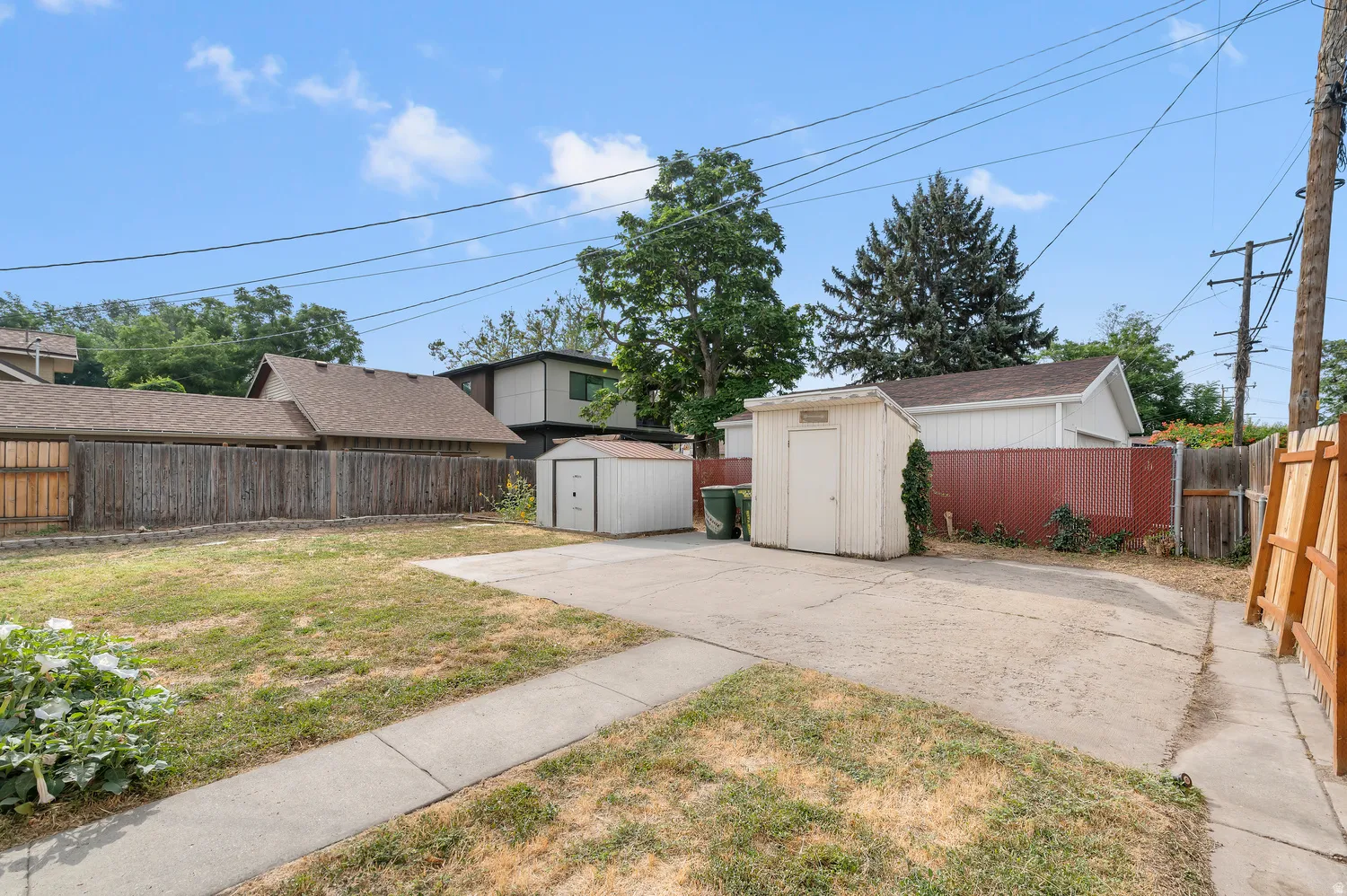 Gated property access, concrete patio, two storage sheds, and a partial wood fence