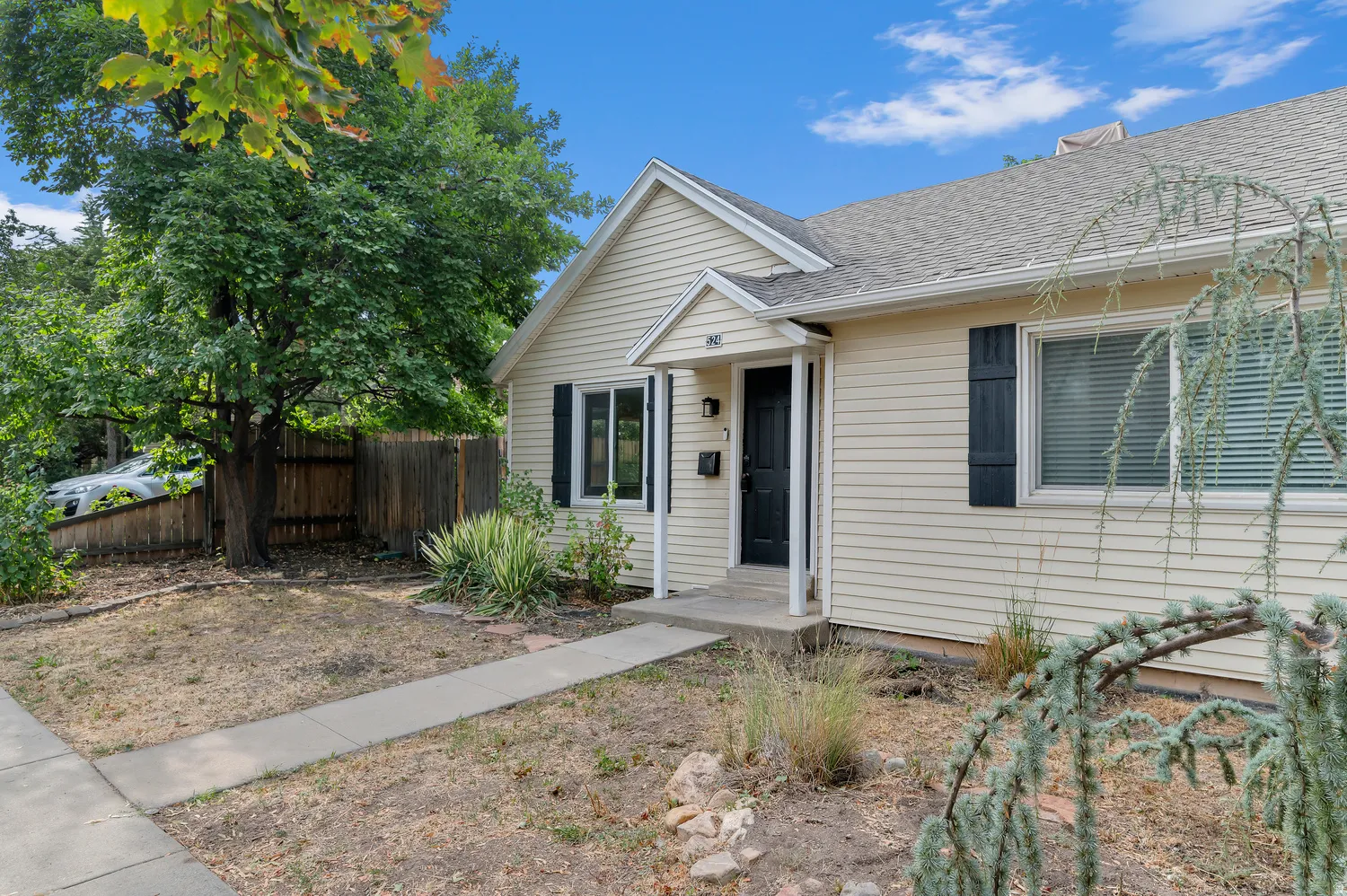Light-colored horizontal siding exterior with a dark front door and black window shutters