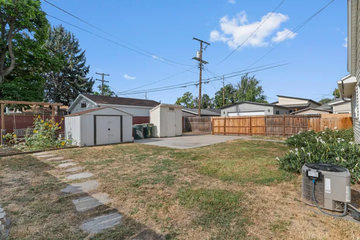 Rear yard with concrete patio, two storage sheds, and a wood fence