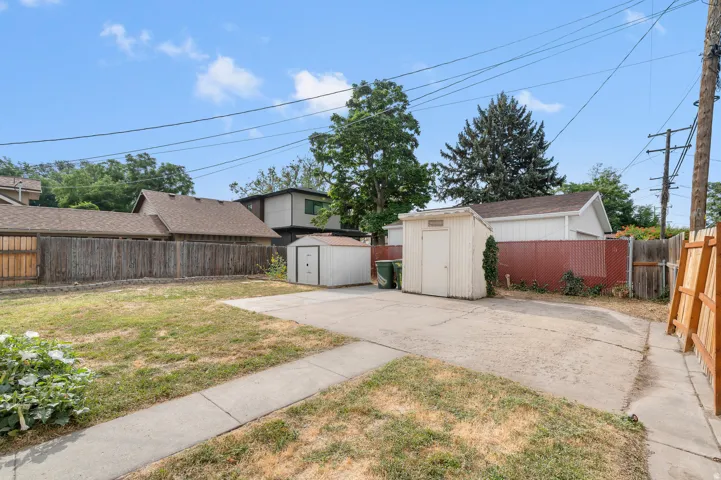 Gated property access, concrete patio, two storage sheds, and a partial wood fence