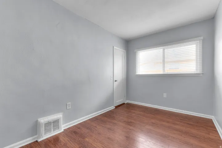 Wood-finish flooring with white baseboards, light blue walls, and a white ceiling