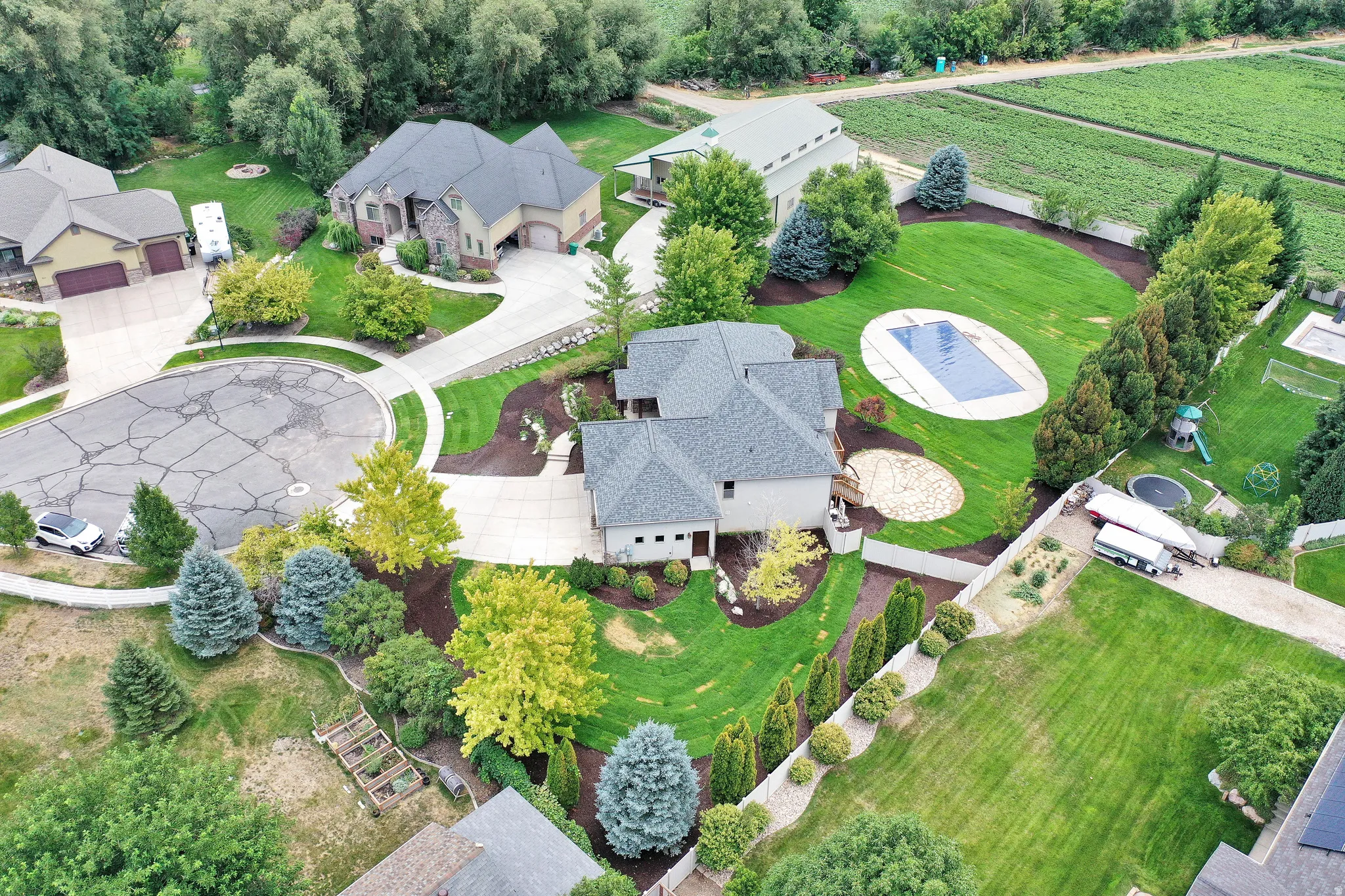 Expansive landscaped property with a covered oval swimming pool, mature trees, and a concrete driveway