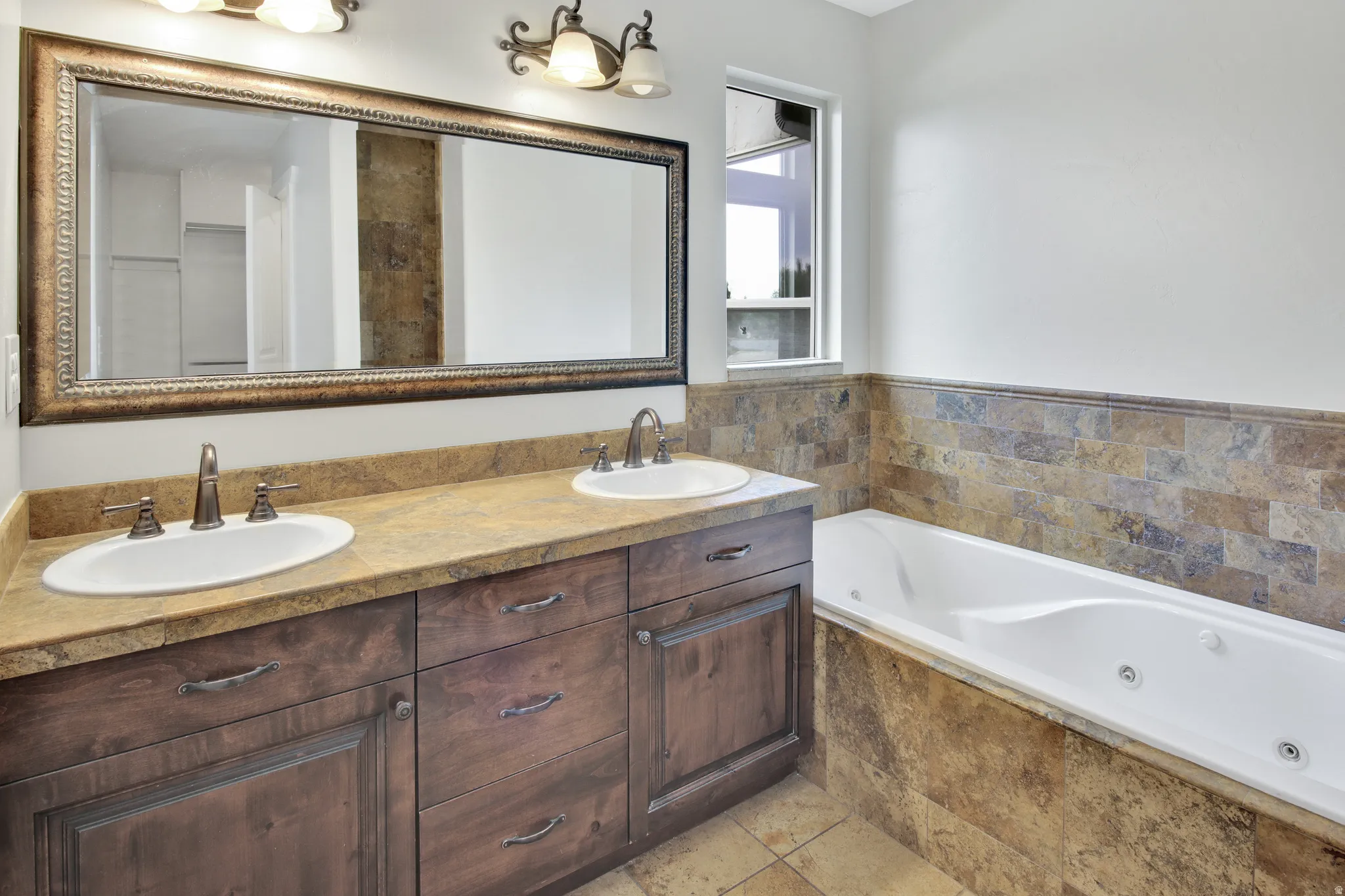 Double vanity with brown wood cabinetry, light brown countertop, and dual undermount sinks