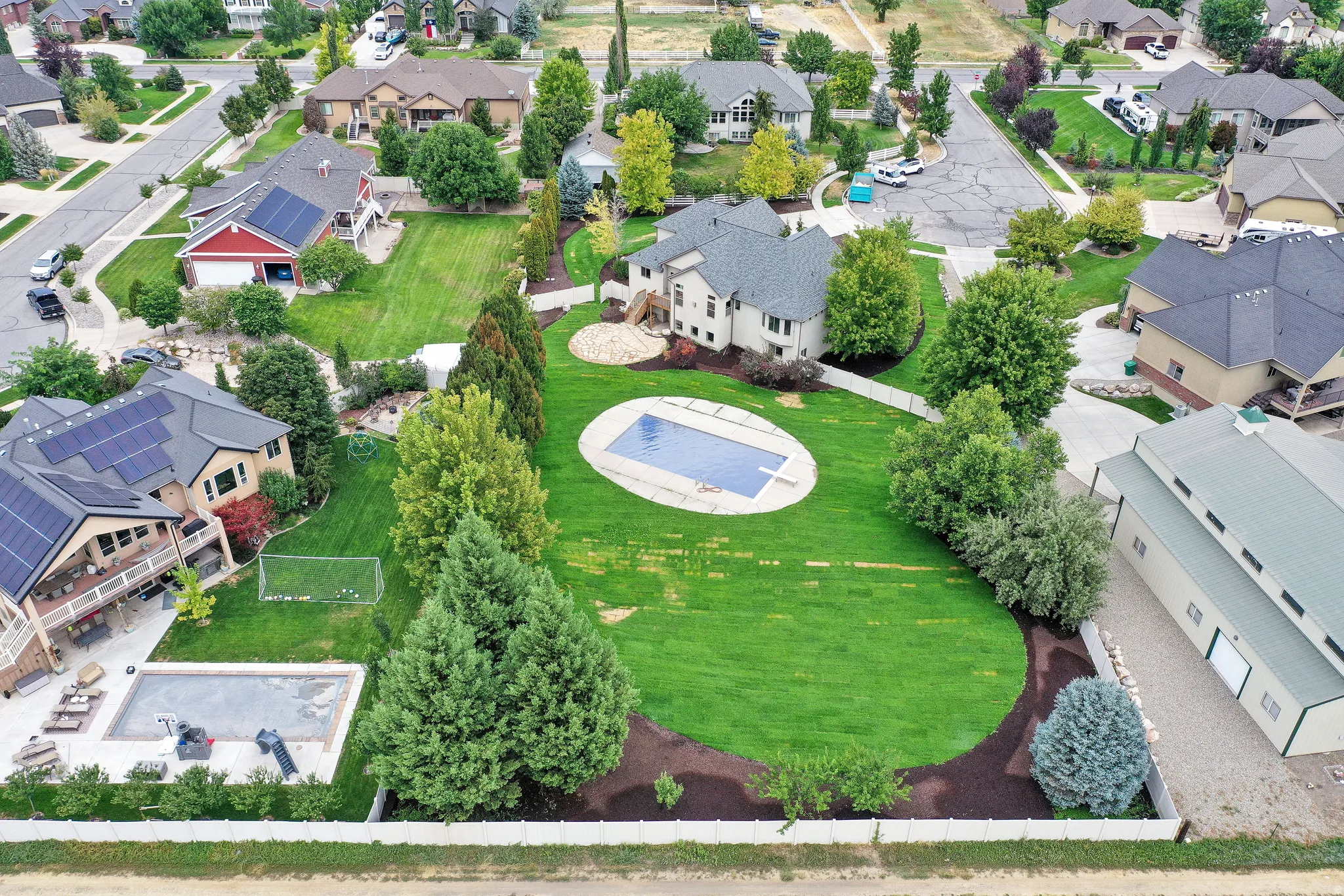 Expansive backyard featuring a large in-ground pool, manicured lawn, and mature trees
