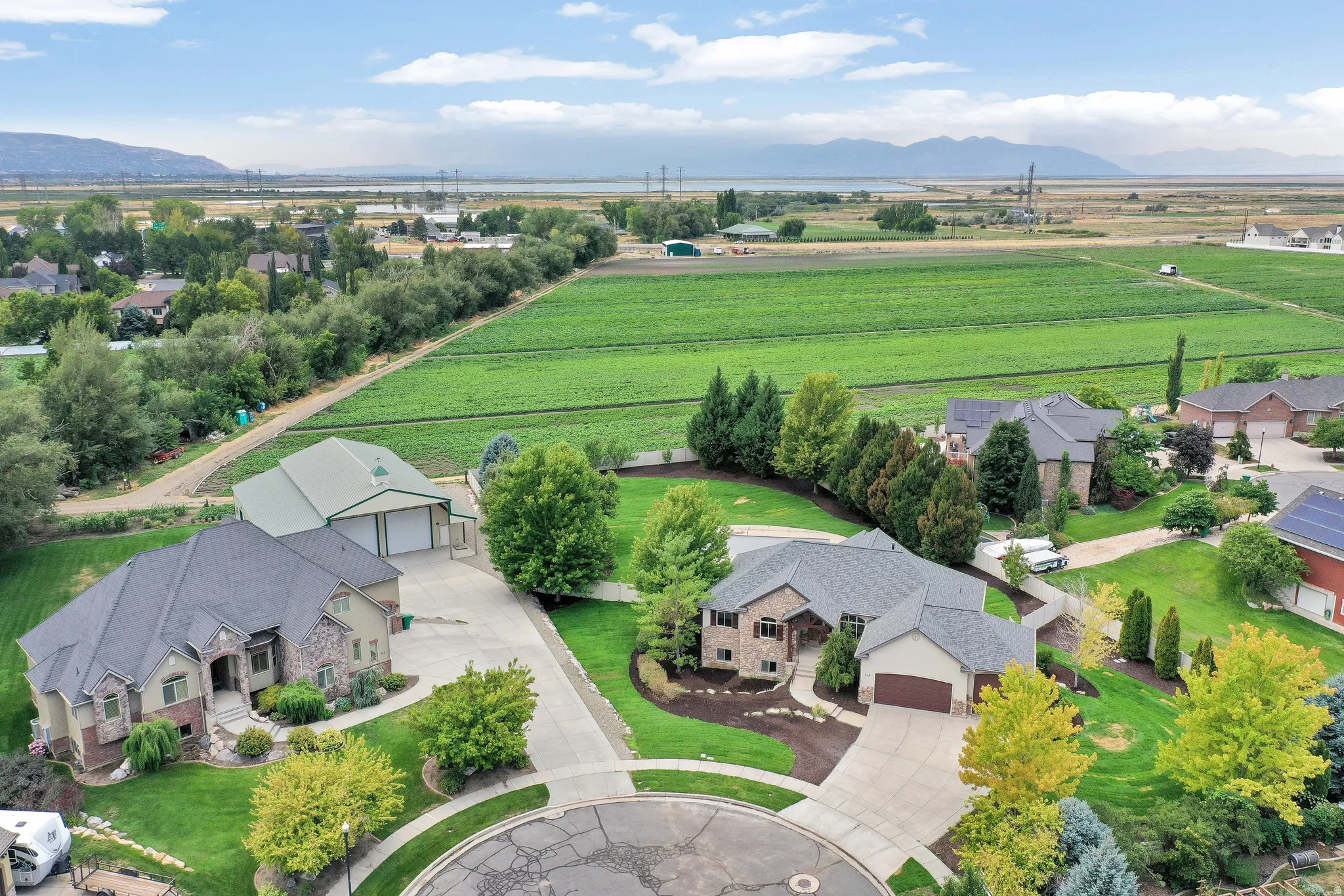 Expansive lot featuring a separate accessory building with multiple garage doors, mature landscaping, and a substantial paved driveway