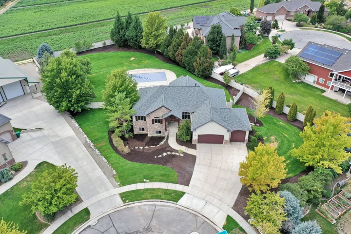 Expansive property featuring a large residence, integrated garage, concrete driveway, lush lawn, and an in-ground pool