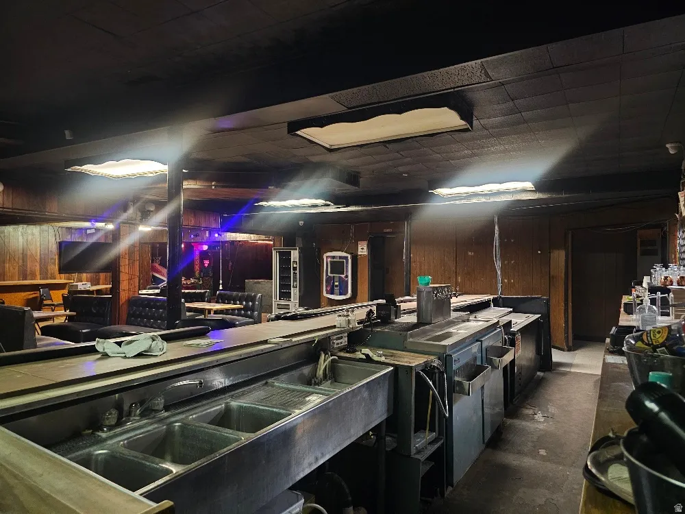 Built-in stainless steel bar sinks, dark paneling, recessed ceiling lighting, and booth seating