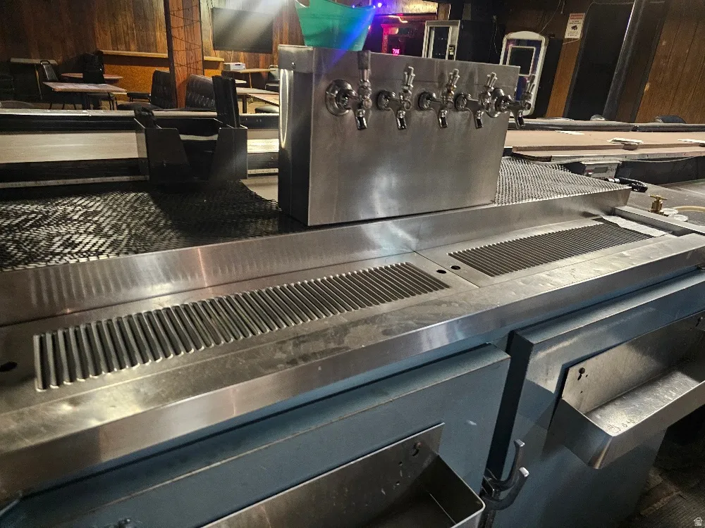 Stainless steel bar top featuring multiple beverage taps and integrated drip trays