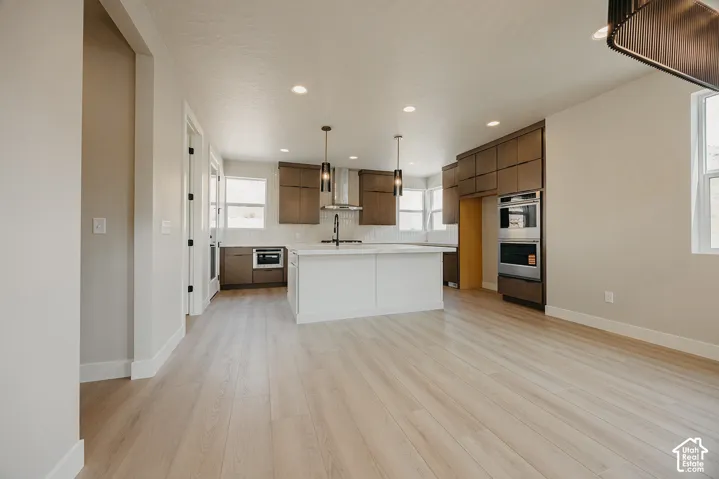 Expansive kitchen featuring wood-finish cabinetry, a large center island with a white countertop, and stainless steel built-in appliances