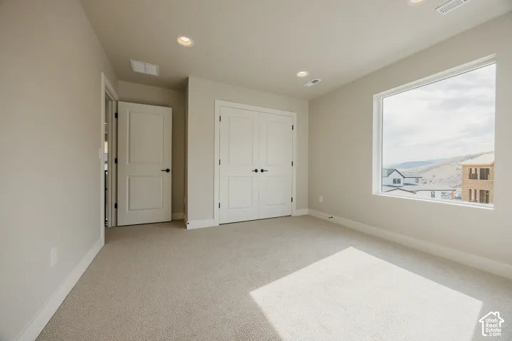 Recessed lighting, light-toned carpeting, white baseboards, and a large window