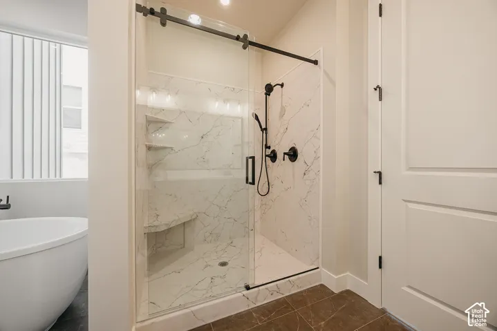 Enclosed shower with sliding glass door, marble-look surround, built-in shelving, and matte black fixtures