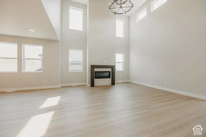 Soaring ceilings, wood-finish flooring, and a contemporary fireplace with a dark wood mantel