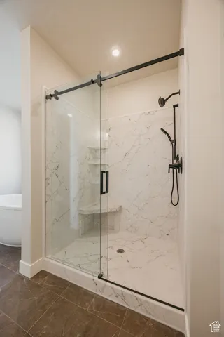 Walk-in shower with clear glass barn door style enclosure, white marble-look tile, built-in bench, and black fixtures