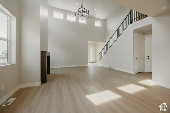 Vaulted ceilings, wood-finish flooring, staircase with metal railings, dark wood-finish mantel, and modern chandelier