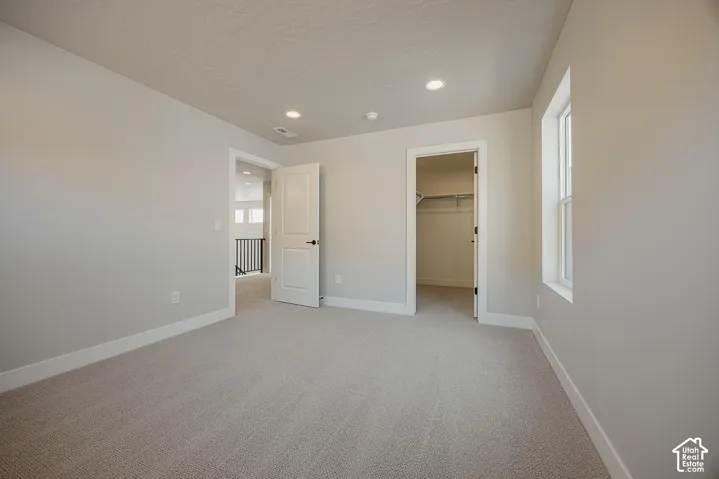 Wall-to-wall carpeting, recessed lighting, and a window with white trim