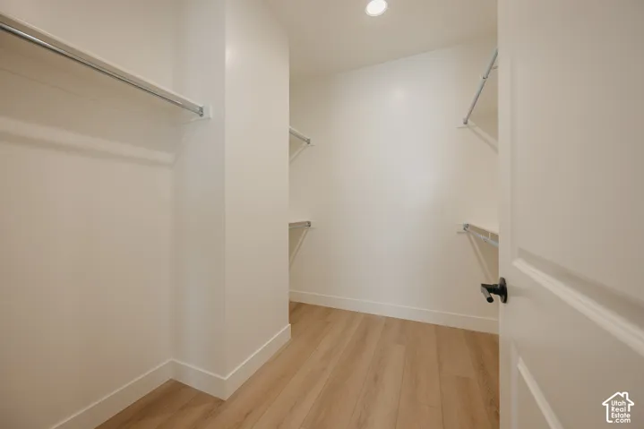 Expansive closet featuring wood-finish flooring, recessed lighting, and multiple shelving and hanging rods