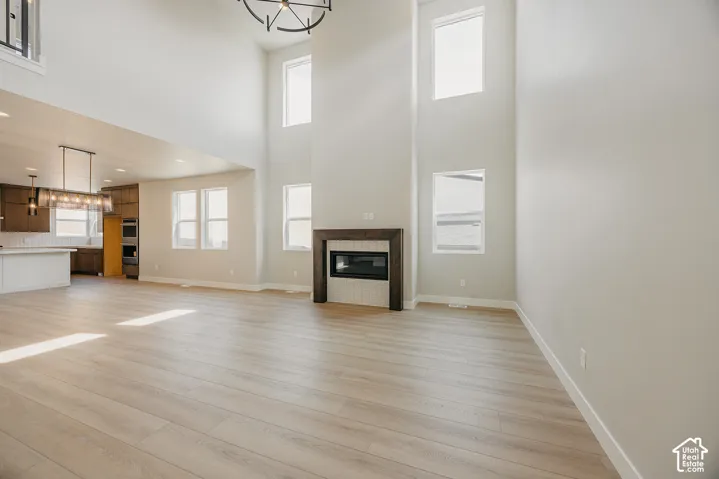 Light wood-finish flooring throughout, two-story ceiling, and a built-in fireplace with a dark wood mantel