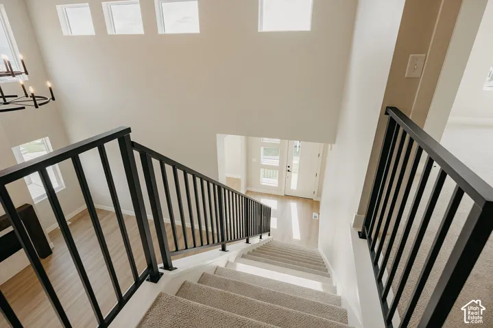 Elegant staircase featuring black metal railings with vertical spindles, wide treads with carpet runner, and abundant natural light from upper-level windows
