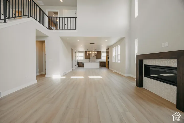 Expansive living area with wood-finish flooring, a contemporary fireplace with a decorative tile surround, and a double-height ceiling