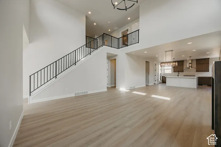 Two-story great room with light wood-finish flooring, recessed lighting, and a contemporary chandelier