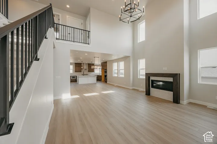 Two-story living area with wood-finish flooring, a contemporary fireplace with a tiled surround, and a dramatic chandelier