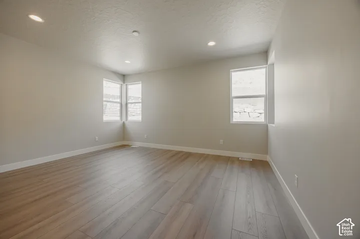 Recessed lighting, wood-finish flooring, multiple windows, and light neutral wall colors