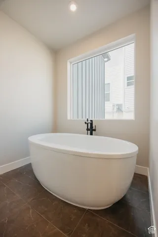 Freestanding oval soaking tub with a matte black floor-mounted faucet, set against a large window