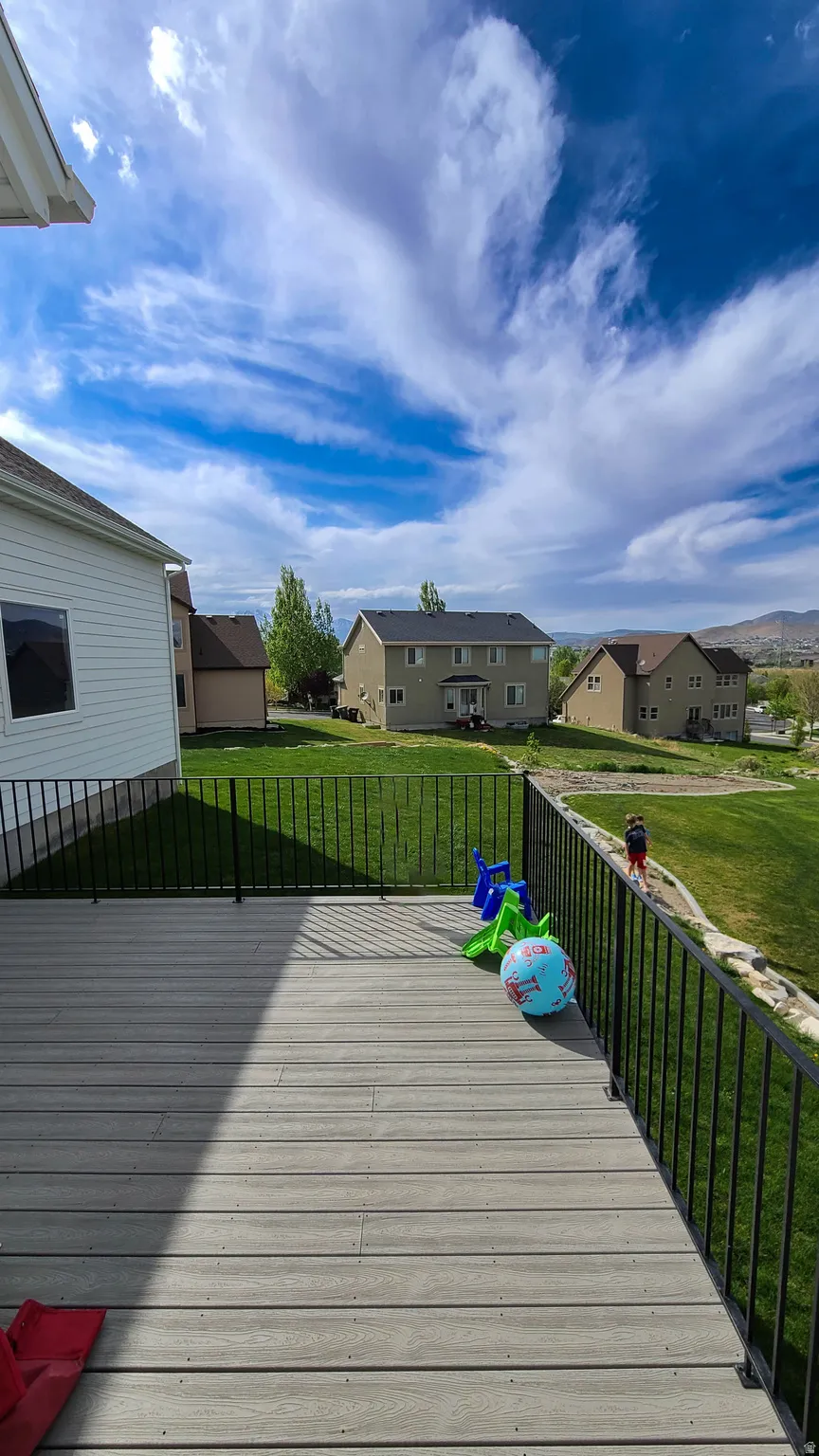 Composite deck with black metal railings overlooking a landscaped yard and distant structures