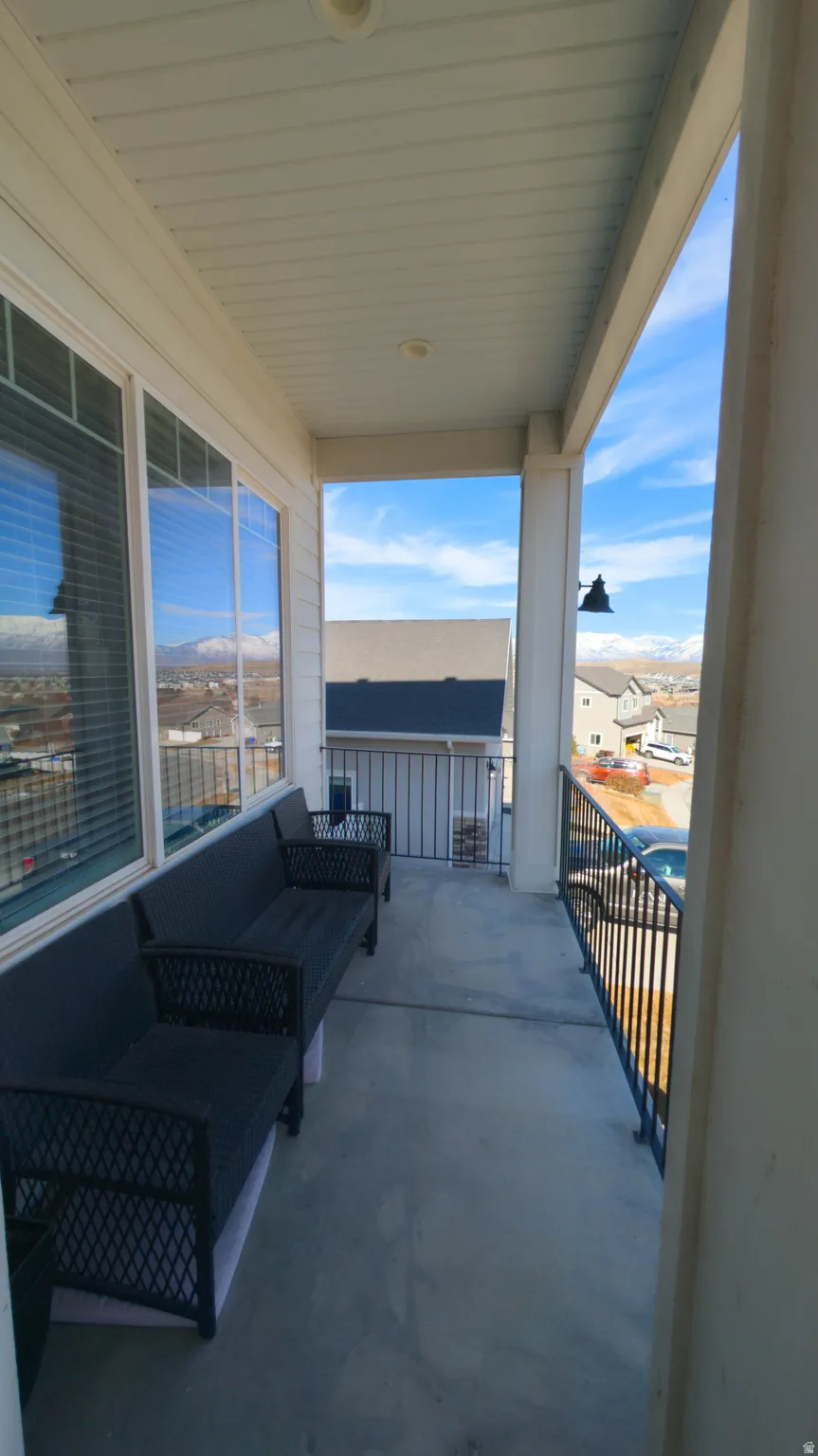 Covered balcony featuring concrete flooring, a white paneled ceiling with recessed lighting, and black metal railings