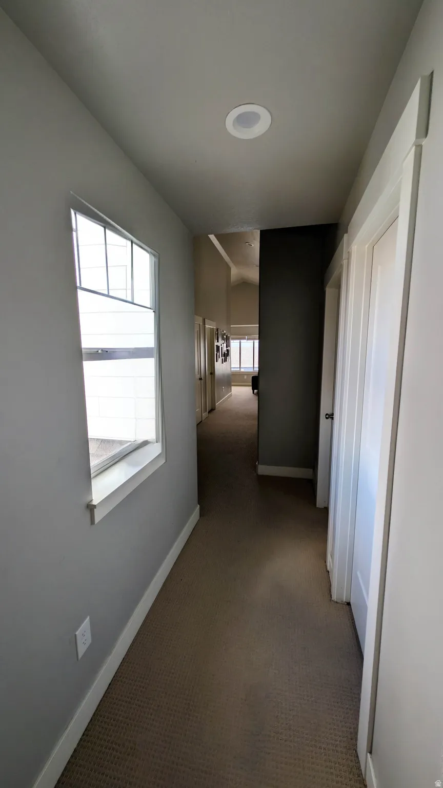 Carpeted hallway with a window, recessed lighting, and white trim