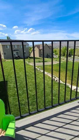 Composite decking with black metal railings overlooking a landscaped backyard and distant properties