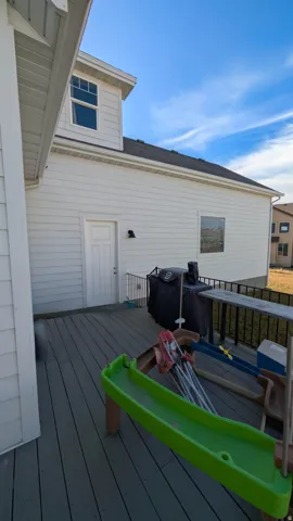 Rear exterior featuring white horizontal siding, a composite deck, black metal railings, and a dormer with multiple windows