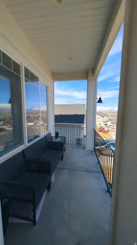 Covered balcony featuring concrete flooring, a white paneled ceiling with recessed lighting, and black metal railings