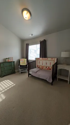 Carpeted room with a ceiling-mounted light fixture and window with blinds