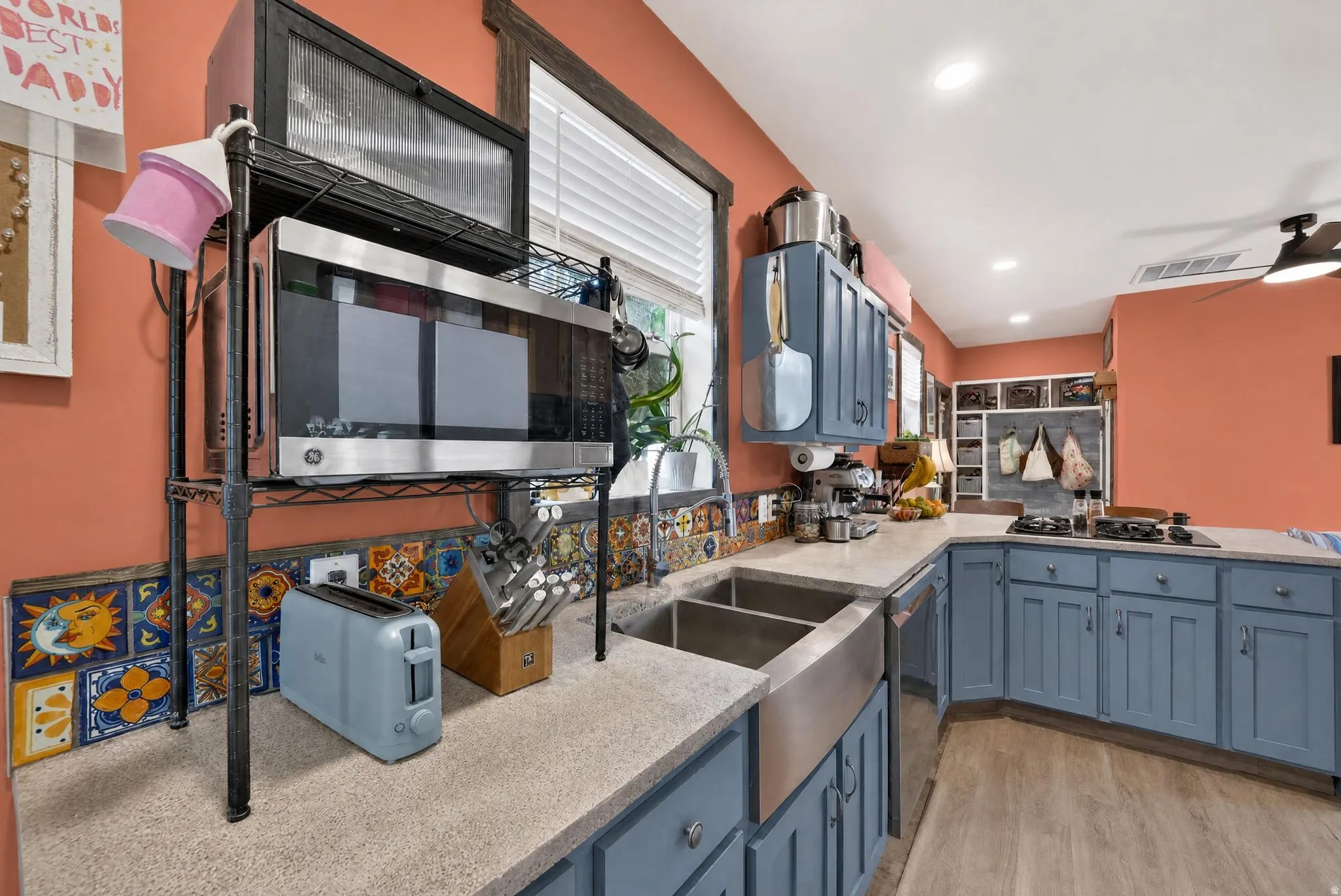 Spacious kitchen featuring an undermount stainless steel sink, custom blue cabinetry, light-colored countertops, and decorative tile backsplash