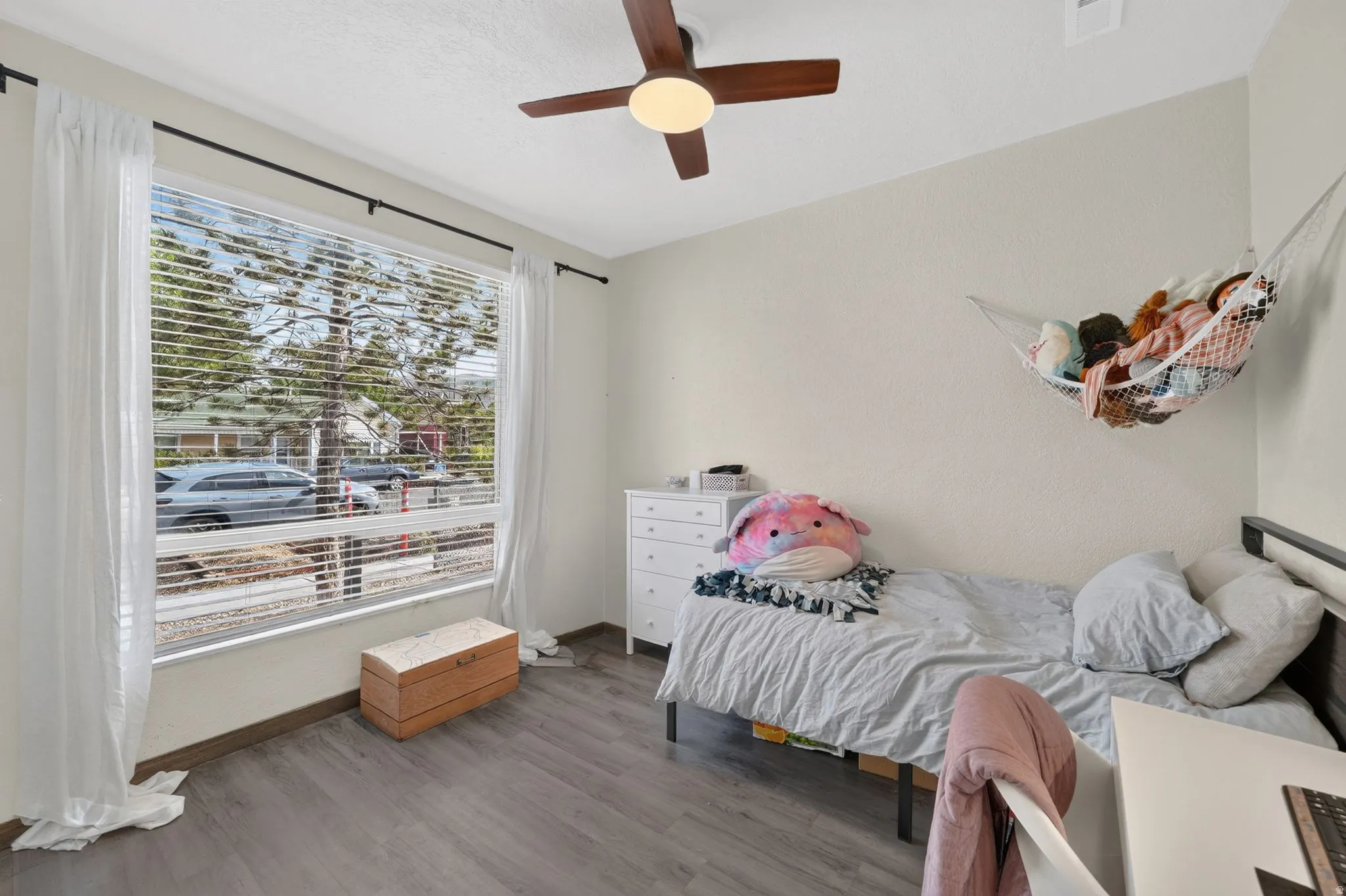 Wide window with horizontal blinds, wood-finish flooring, and a ceiling fan with integrated lighting