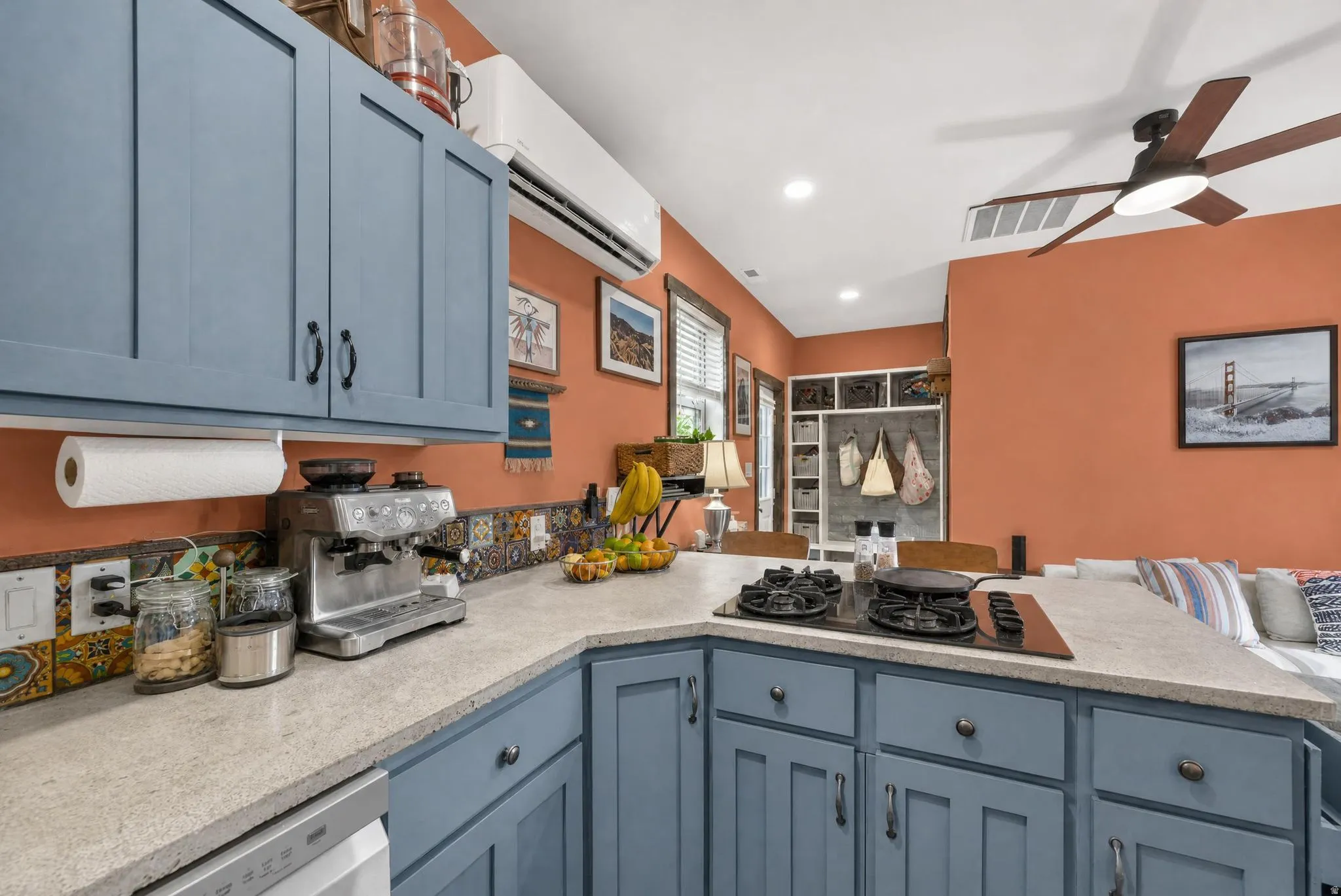 Kitchen featuring blue cabinetry, a built-in cooktop, light-toned countertops, and a decorative tile backsplash